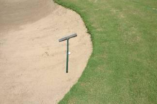 Improper placement of bunker rake with ball resting against rake as a result