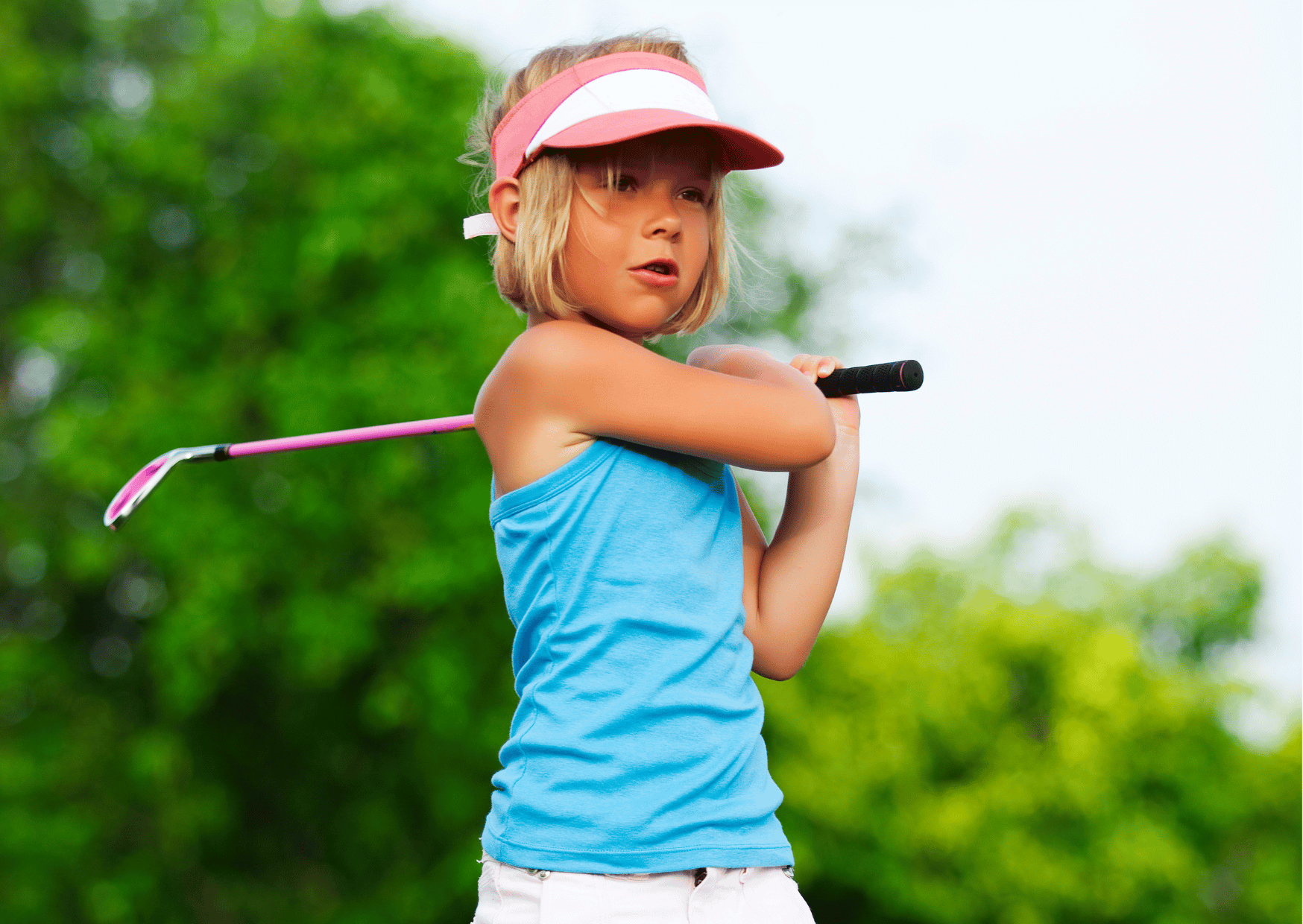 Young girl holding her pose after hitting a golf ball