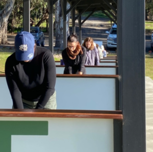 People lined up in different bays at the driving range getting ready to begin their golf lesson